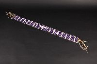 This wampum belt has several motifs made with white beads contrasted with purple ones. The central motif is an axe.